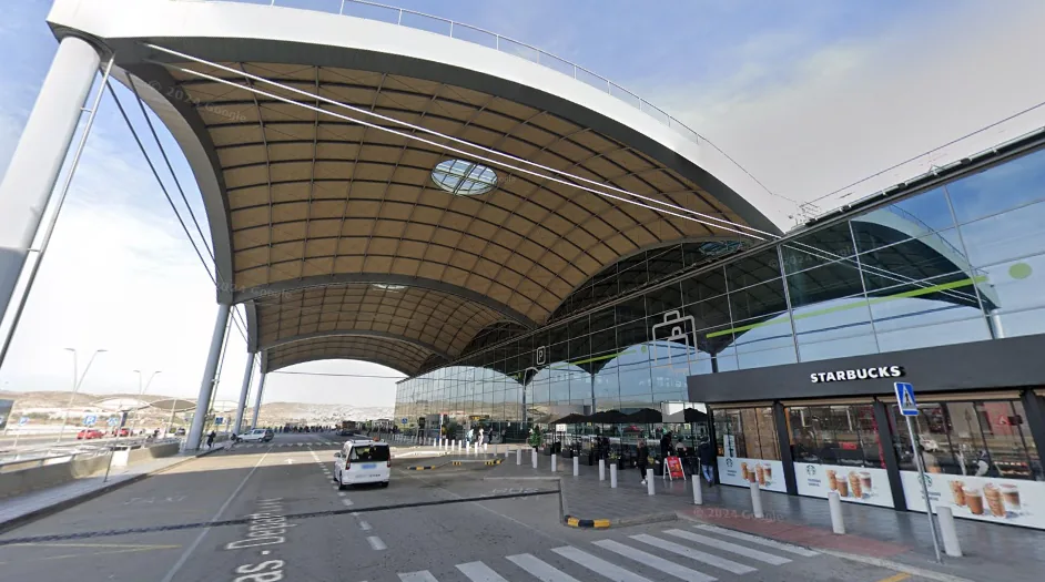 Alicante Airport terminal exterior with passengers and palm trees