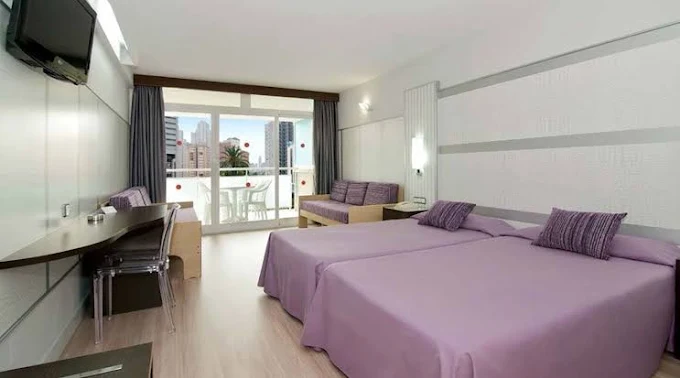 Twin room at Flamingo Oasis Benidorm with purple bedding, balcony and Benidorm skyline view