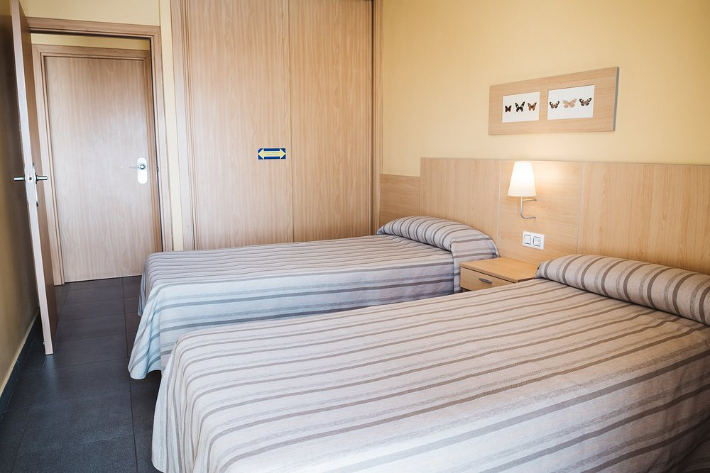 Twin bedroom inside a Terralta apartment with wood headboard and bedside lamp