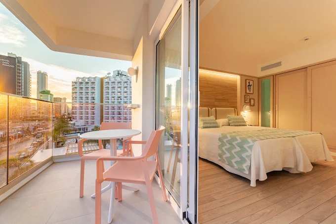 Refurbished bedroom with private balcony overlooking Benidorm skyline at sunset