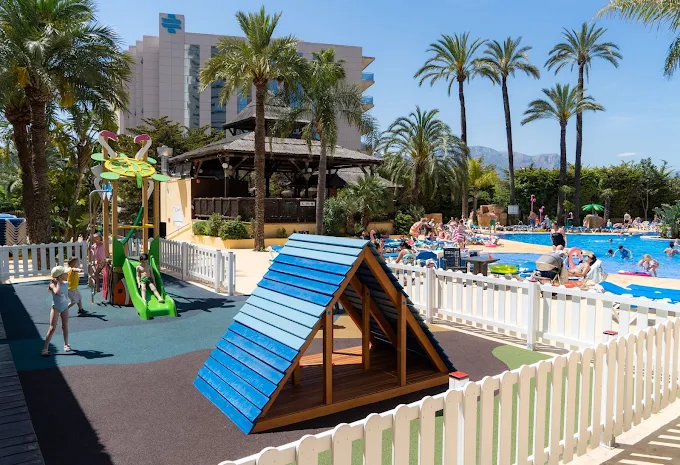 Fenced outdoor playground and slide next to the pool at Flamingo Oasis Benidorm
