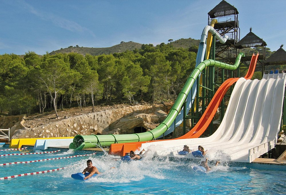 Verti-Go tower at Aqualandia Benidorm Tall Verti-Go drop slide tower at Aqualandia Benidorm rising above trees and spectators in the waterpark