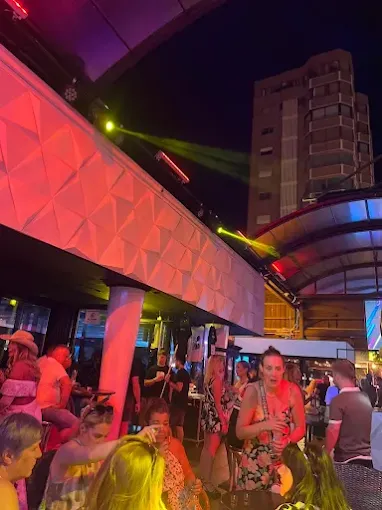 Outdoor terrace crowd at Insomnia Benidorm under pink lights