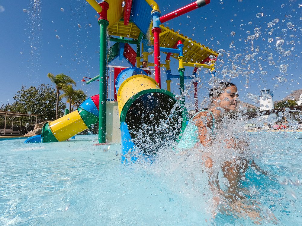 Child splashing in the colourful water play area at Magic Natura