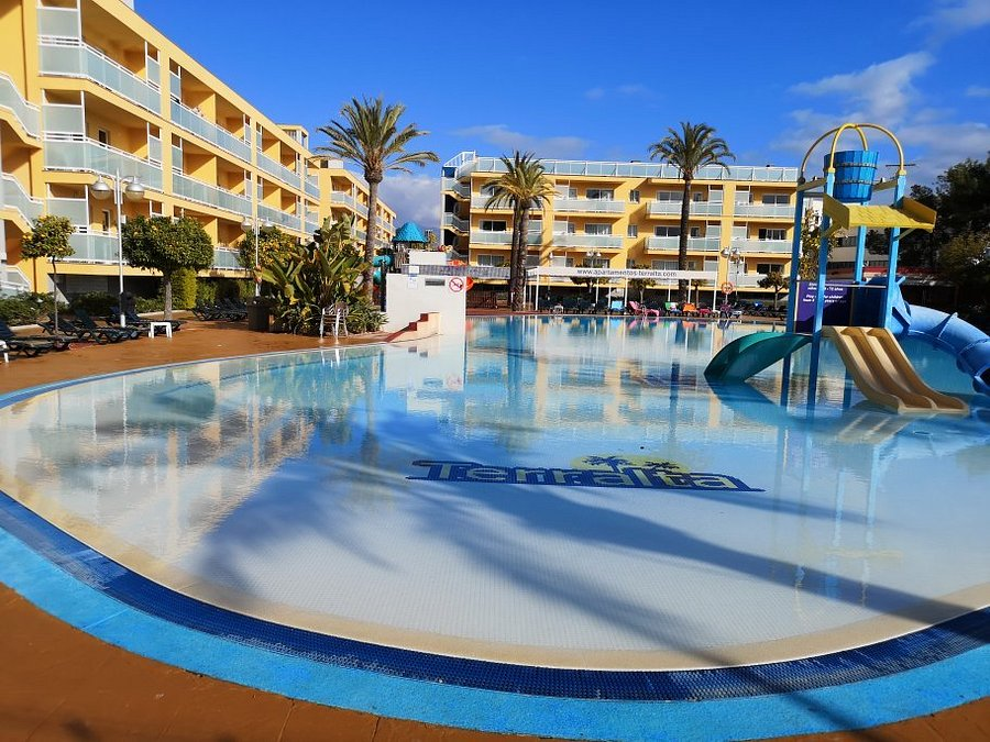 Daytime view of the Terralta Apartments Benidorm pool, slides and yellow apartment buildings